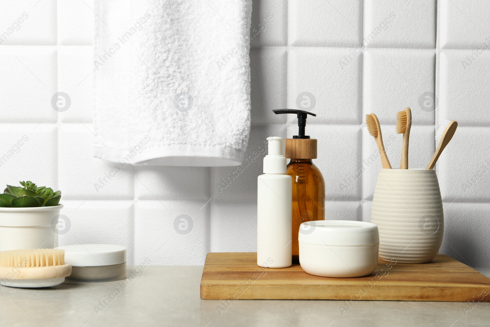 Photo of Different bath accessories and personal care products on gray table near white tiled wall