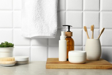 Different bath accessories and personal care products on gray table near white tiled wall