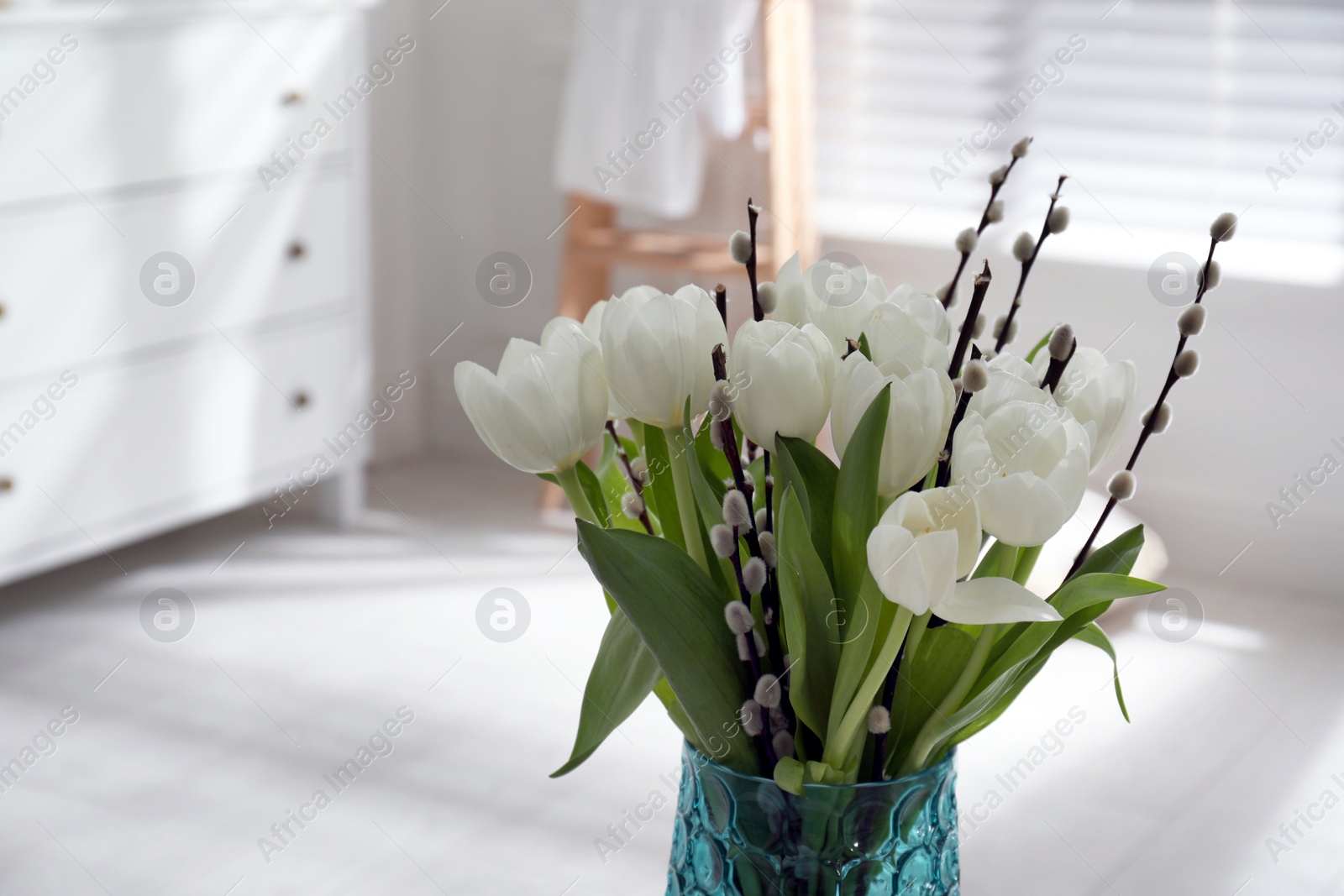 Photo of Beautiful bouquet of willow branches and tulips in vase indoors, space for text