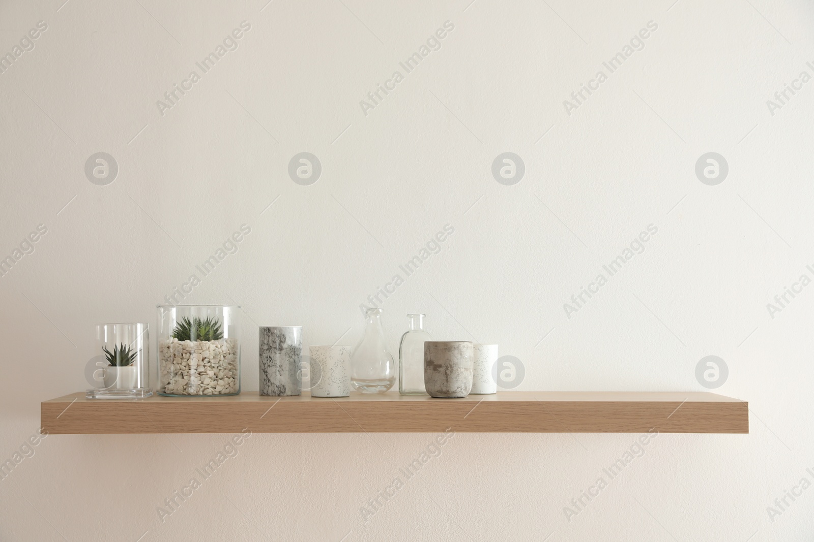 Photo of Wooden shelf with plants and decorative elements on light wall