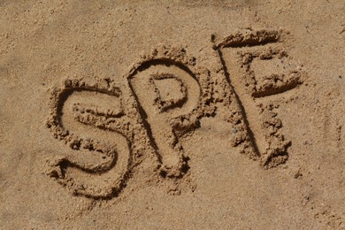 Photo of Abbreviation SPF written on sand at beach, above view
