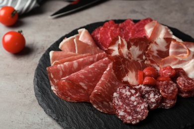 Photo of Slate plate with different meat delicacies on gray table