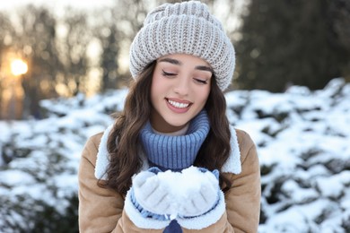 Portrait of smiling woman holding pile of snow in park