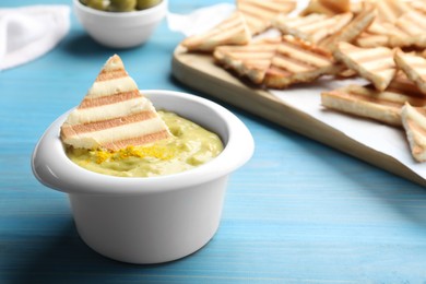 Delicious pita chips and hummus on light blue wooden table, closeup