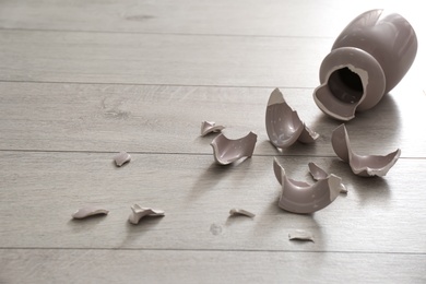 Photo of Broken pink ceramic vase on wooden floor