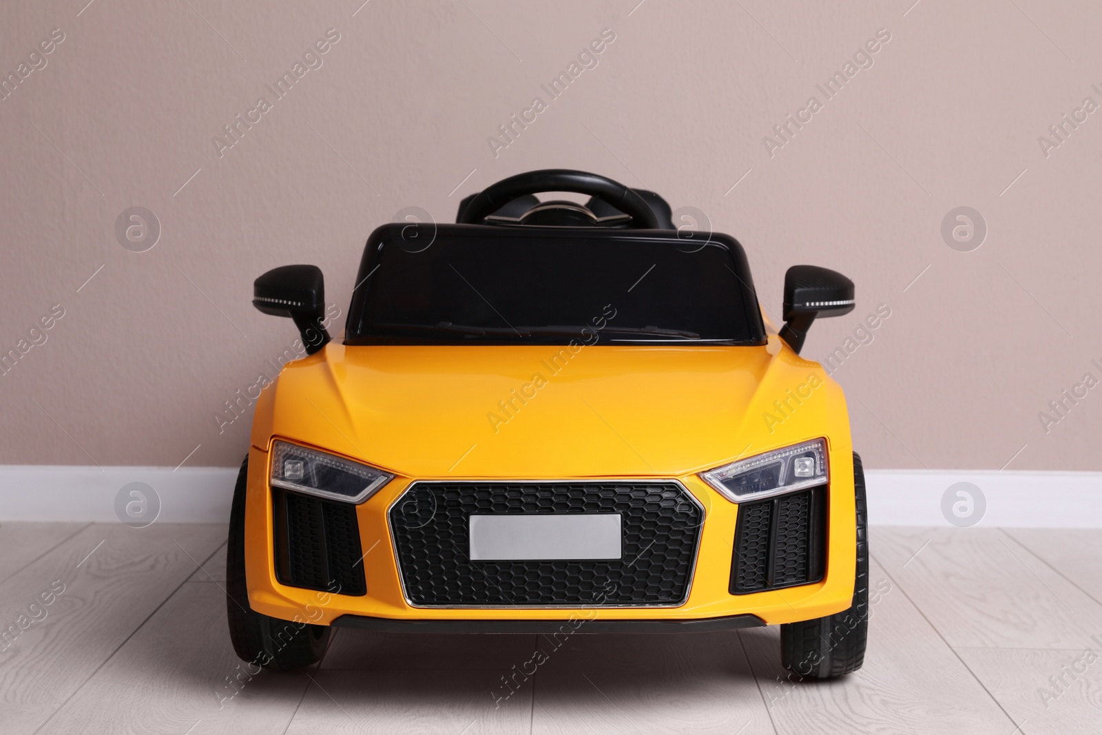 Photo of Child's electric toy car near beige wall indoors