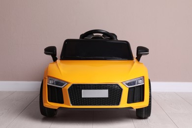 Photo of Child's electric toy car near beige wall indoors