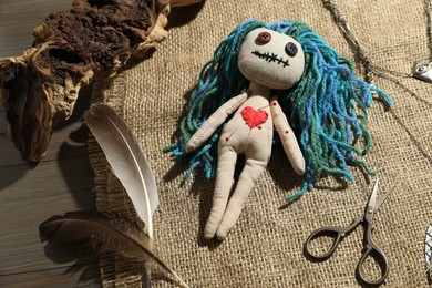 Photo of Voodoo doll with pins surrounded by ceremonial items on wooden table