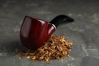 Pile of tobacco and smoking pipe on grey table
