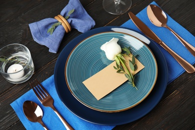 Elegant festive table setting with blank card on black wooden background