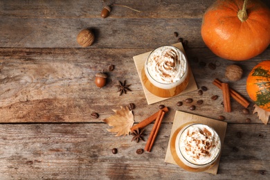 Photo of Flat lay composition with glasses of tasty pumpkin spice latte and space for text on wooden background
