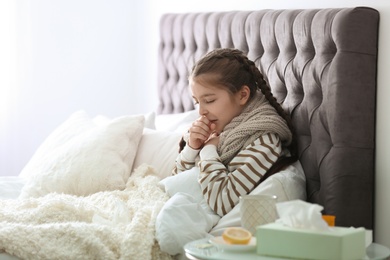 Photo of Sick little girl with cough suffering from cold in bed