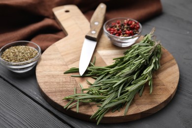Wooden board, knife and spices on grey table, closeup