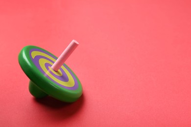 Photo of One colorful spinning top on red background, space for text