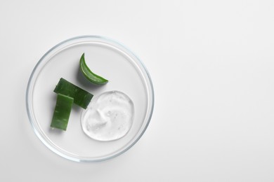 Photo of Petri dish with cosmetic gel and pieces of aloe vera on white background, top view. Space for text