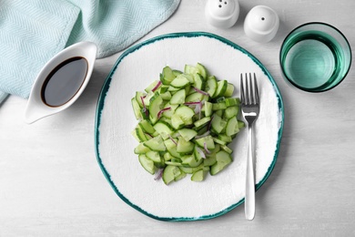 Plate of vegetarian salad with cucumber and onion served on table, flat lay