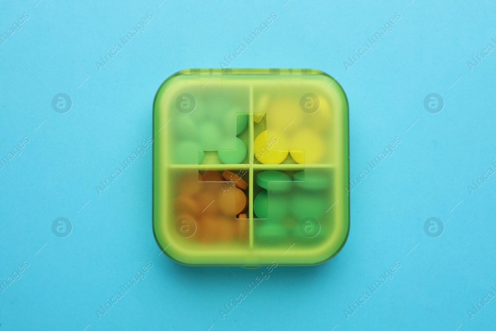 Photo of Pill box with medicaments on light blue background, top view