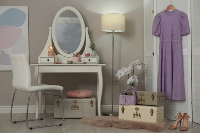 Photo of Stylish storage trunks, dressing table and beautiful orchid flower in room. Interior design