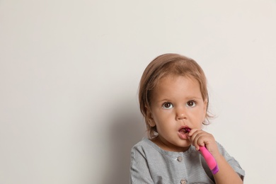 Cute little girl with toothbrush and space for text on white background