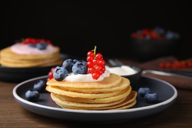 Photo of Tasty pancakes with natural yogurt, blueberries and red currants on wooden table. Space for text