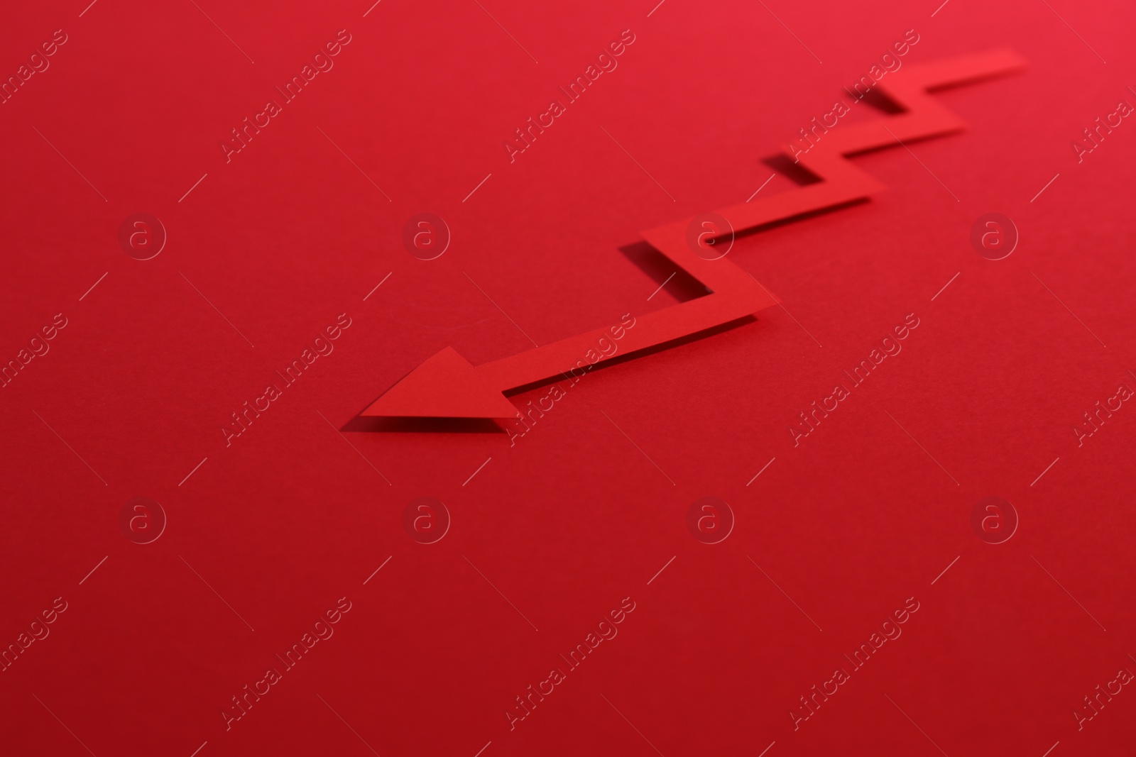 Photo of One zigzag paper arrow on red background, closeup. Space for text