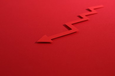 Photo of One zigzag paper arrow on red background, closeup. Space for text