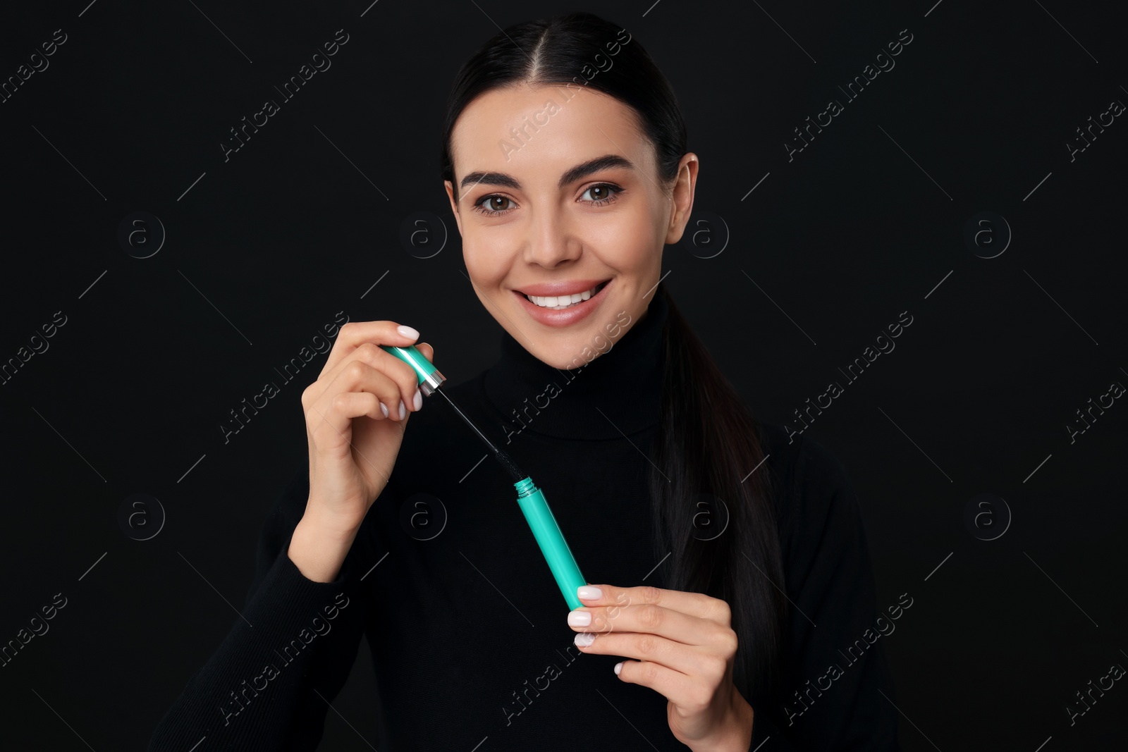 Photo of Beautiful young woman with mascara on black background