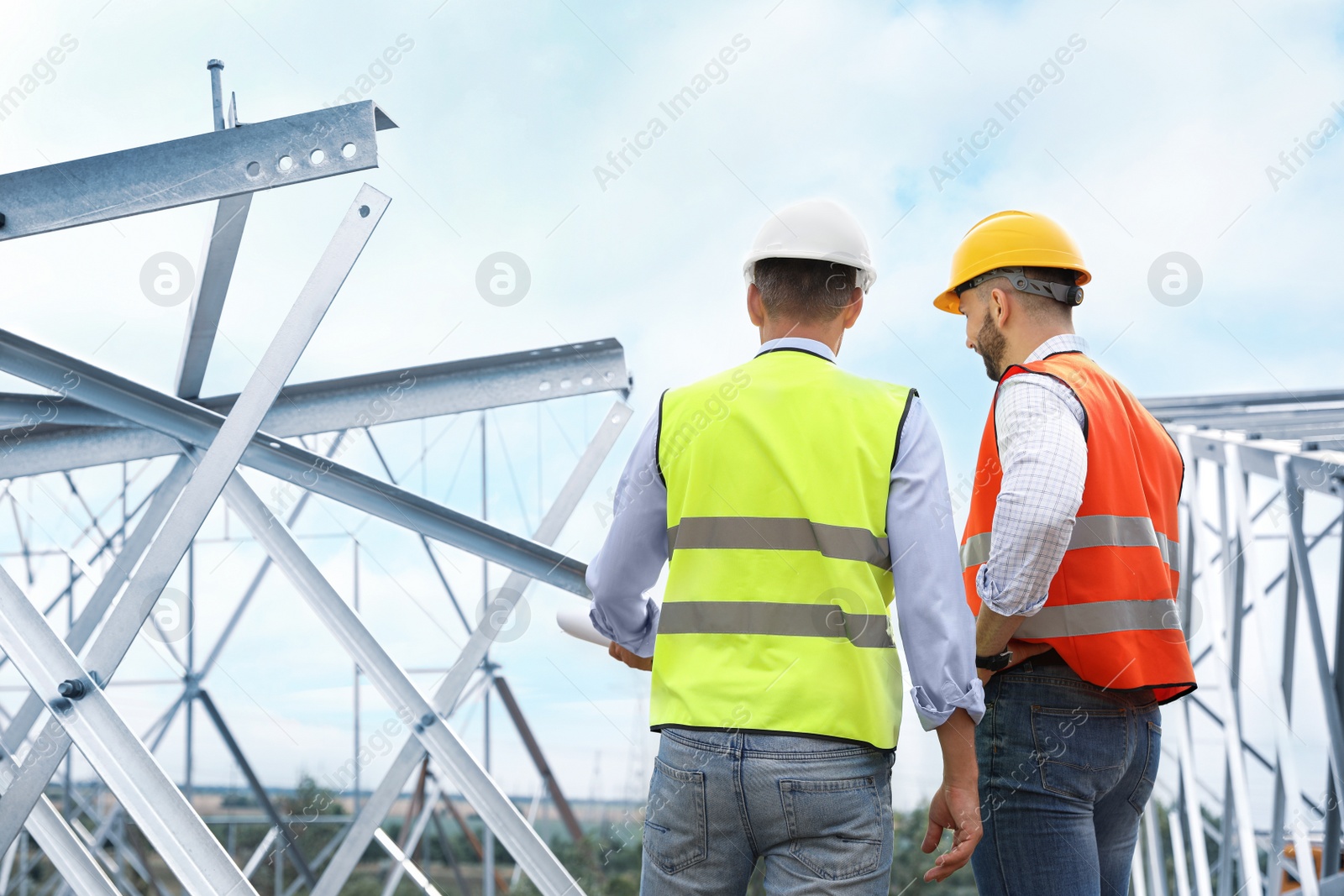 Photo of Professional engineers working on installation of electrical substation outdoors, back view