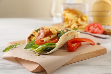 Photo of Delicious pita wrap with jamon, vegetables and greens on wooden table