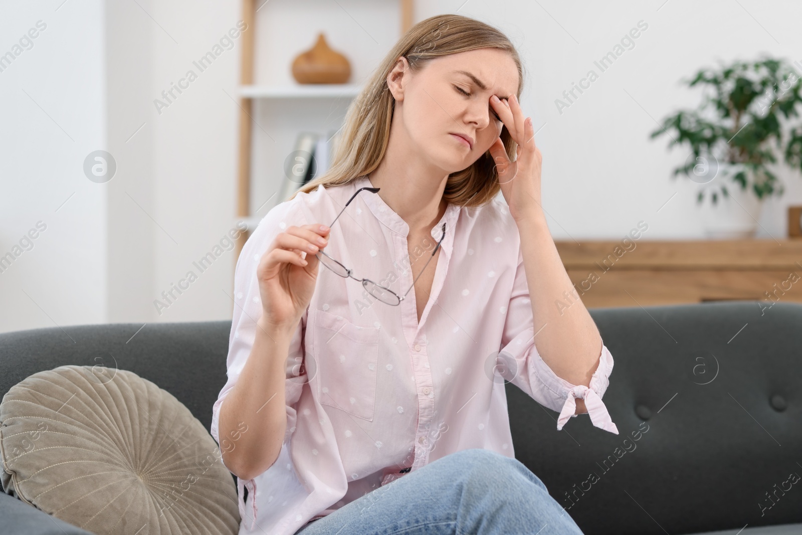 Photo of Overwhelmed young woman with glasses suffering from headache at home