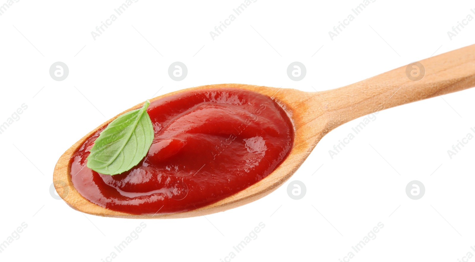 Photo of Wooden spoon with tasty ketchup and basil isolated on white