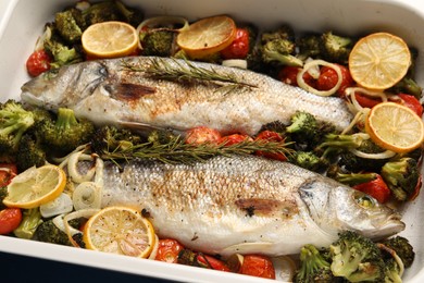 Photo of Delicious fish with vegetables and lemon in baking dish on table, closeup