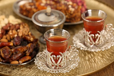 Glasses with tasty Turkish tea and sweets on wooden table