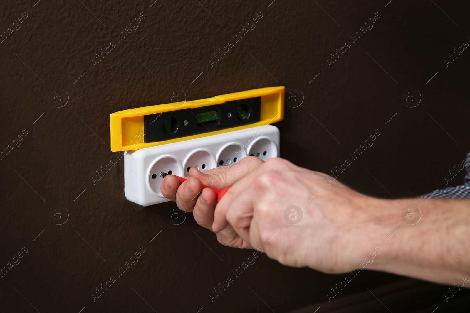 Photo of Electrician with screwdriver repairing power socket, closeup