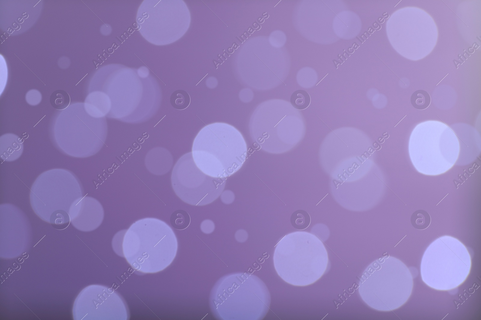 Photo of Blurred view of festive lights on violet background. Bokeh effect