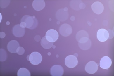 Blurred view of festive lights on violet background. Bokeh effect