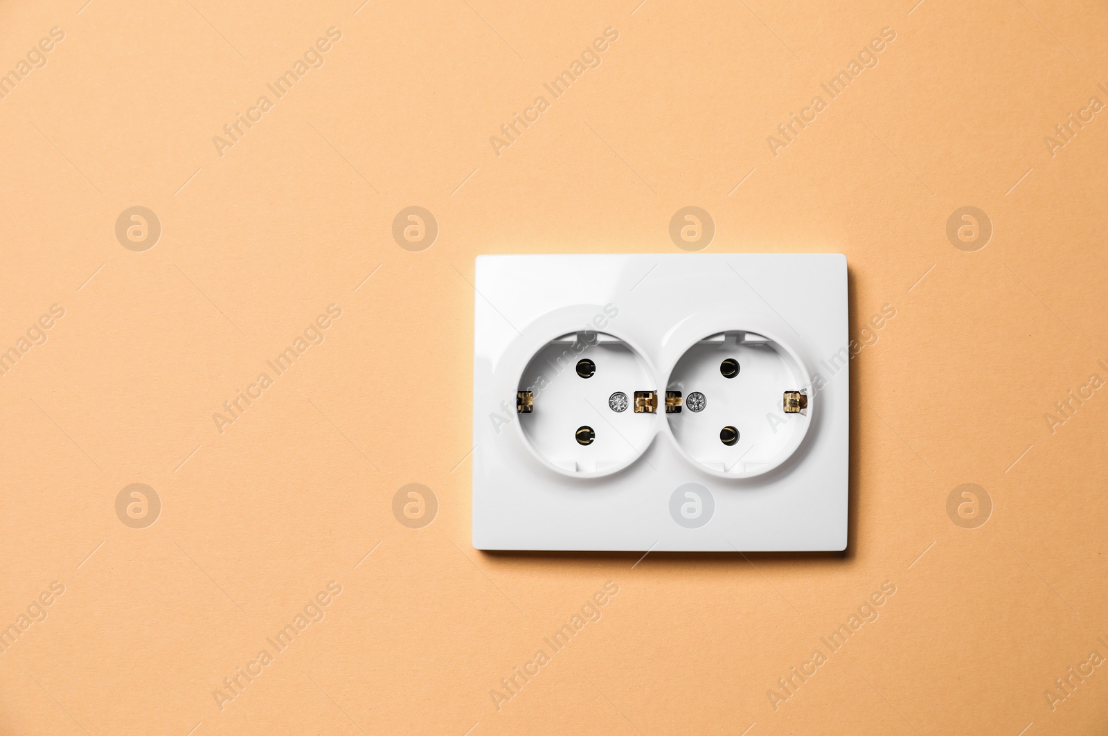 Photo of Double power socket on pale orange wall, space for text. Electrical supply