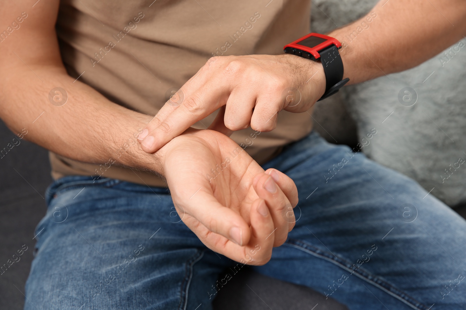 Photo of Man checking pulse with fingers at home, closeup
