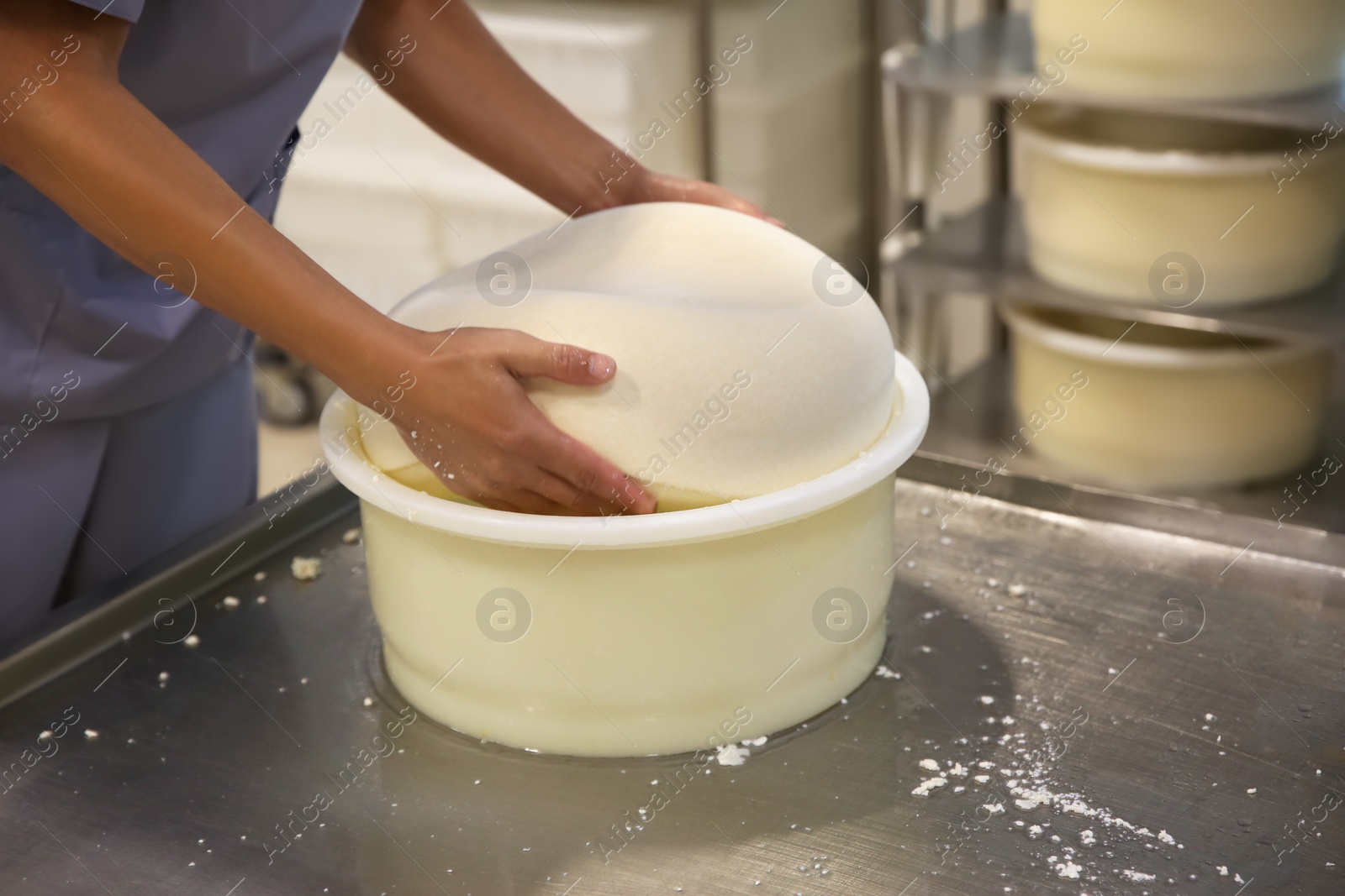 Photo of Worker taking fresh cheese from mould at modern factory, closeup