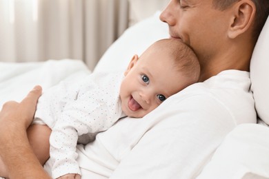 Photo of Father holding his cute baby on bed at home, closeup