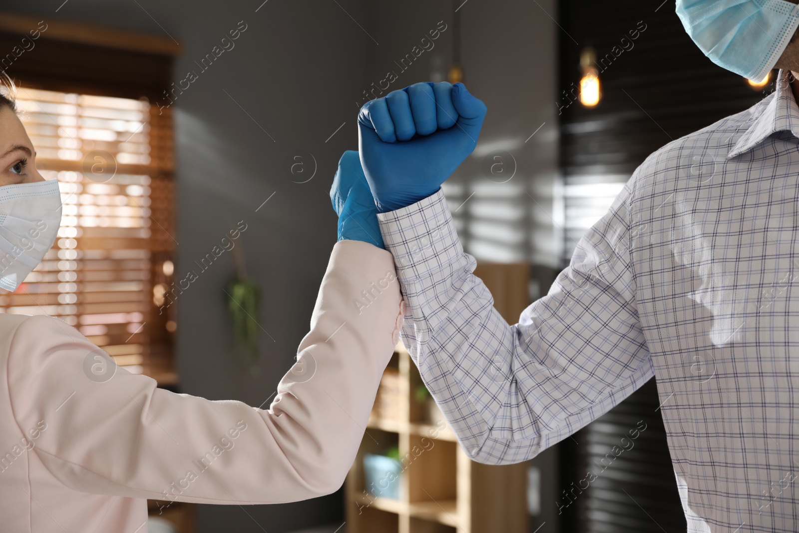 Photo of People greeting each other by bumping fists instead of handshake in office, closeup