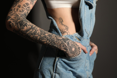 Photo of Woman with tattoos on body against black background, closeup