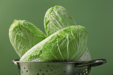 Fresh Chinese cabbages in colander on green background, closeup