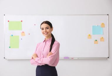 Young teacher near whiteboard in modern classroom. Space for text