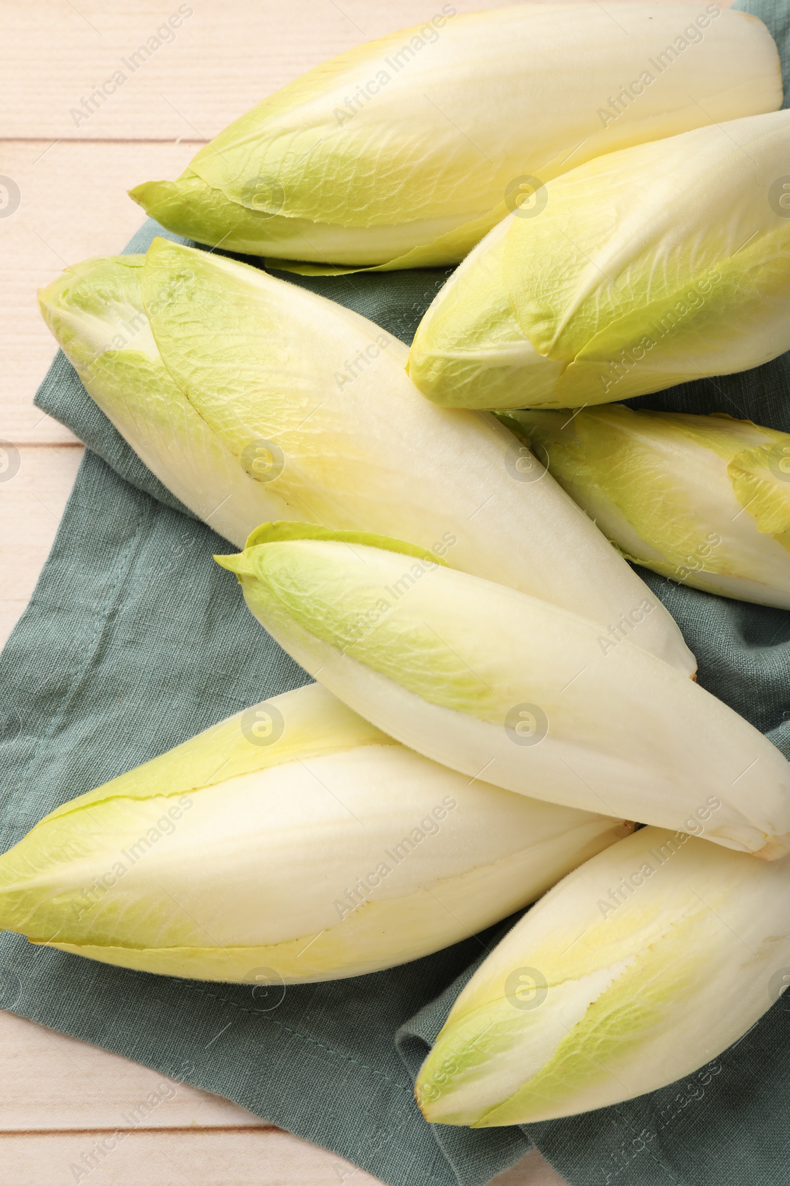 Photo of Raw ripe chicories on wooden table, top view