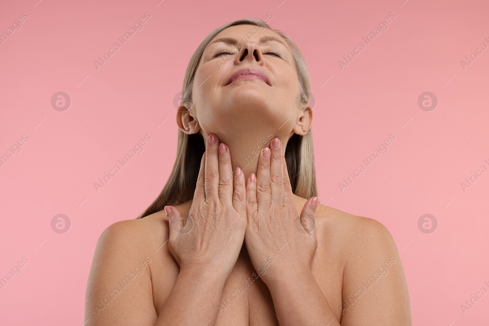 Photo of Beautiful woman touching her neck on pink background