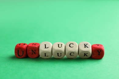 Photo of Red and white cubes with word UNLUCKY on green background, closeup