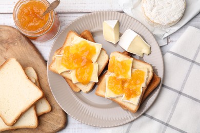 Photo of Tasty sandwiches with brie cheese and apricot jam on white wooden table, flat lay