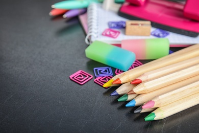 Photo of Different colorful stationery on chalkboard surface. Back to school