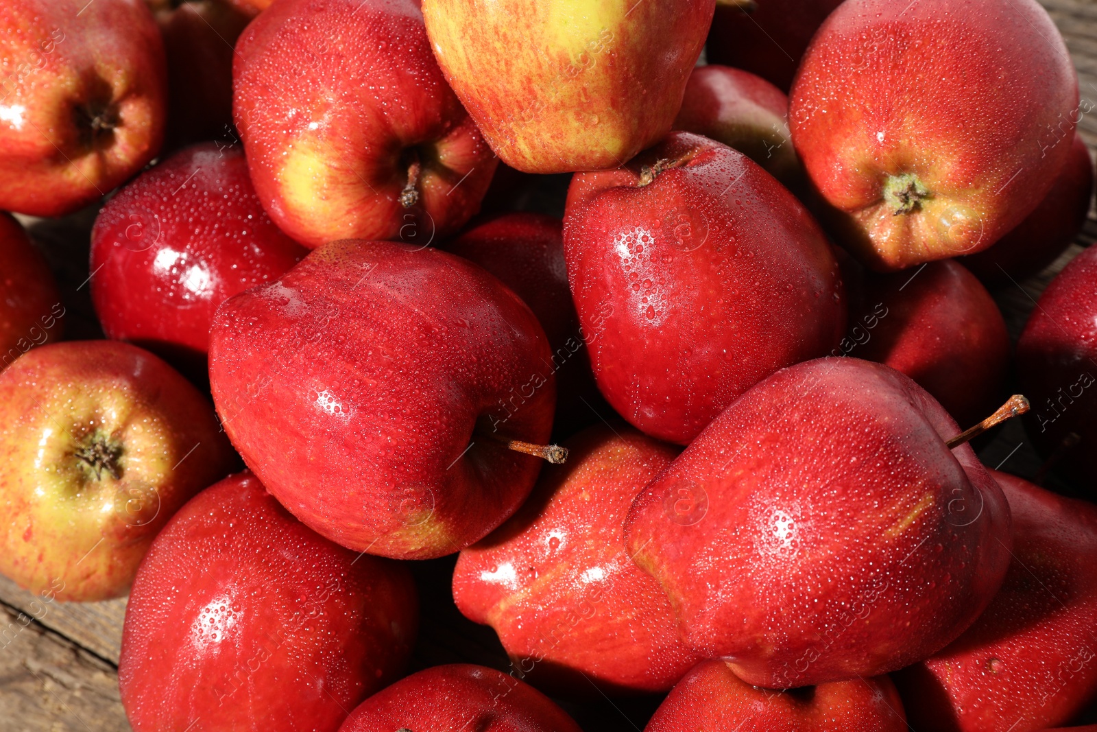 Photo of Many fresh apples with water drops on wooden table, above view